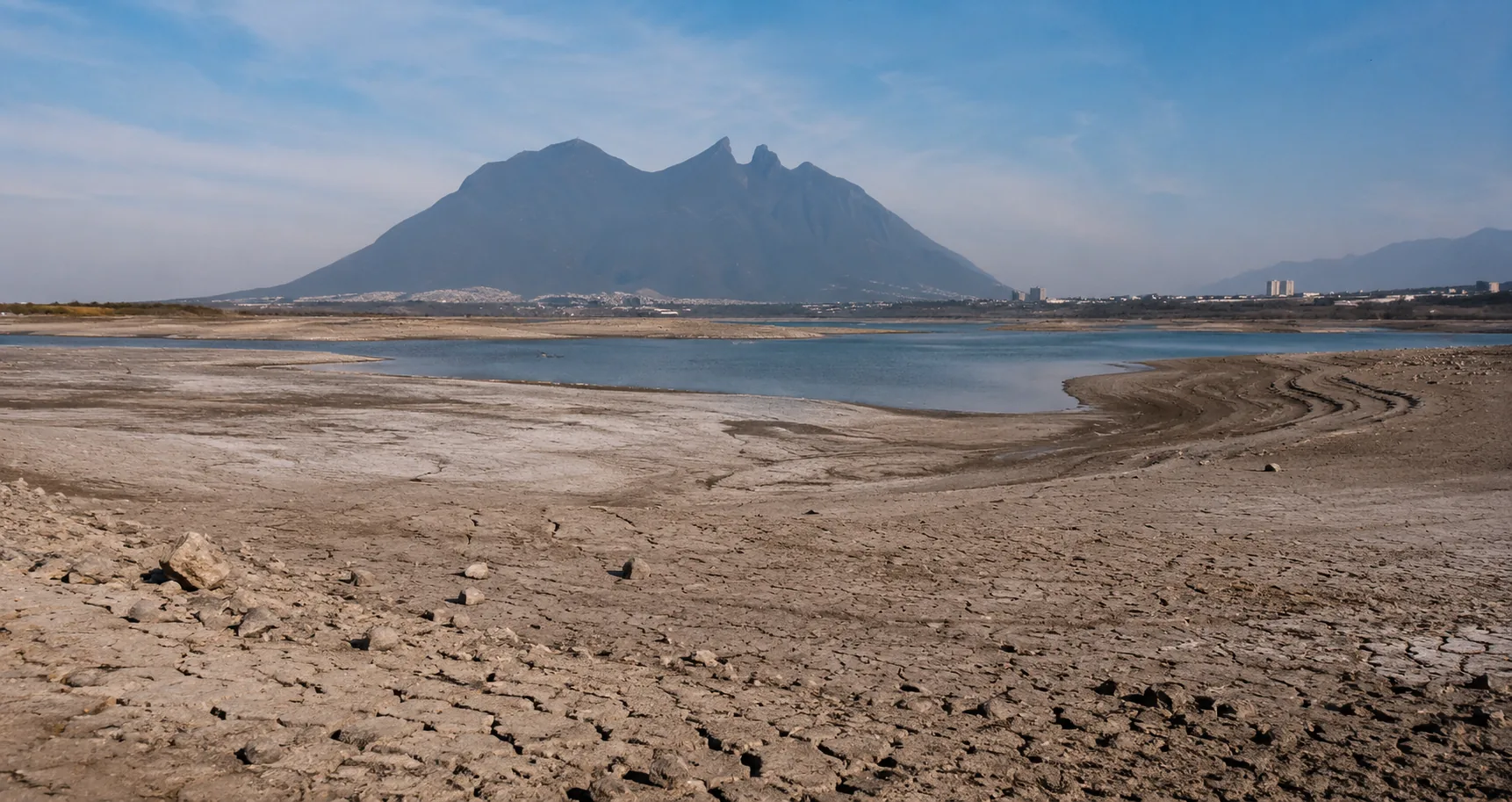 Presa El Cuchillo con bajo nivel de agua y tierra agrietada expuesta bajo cielo despejado