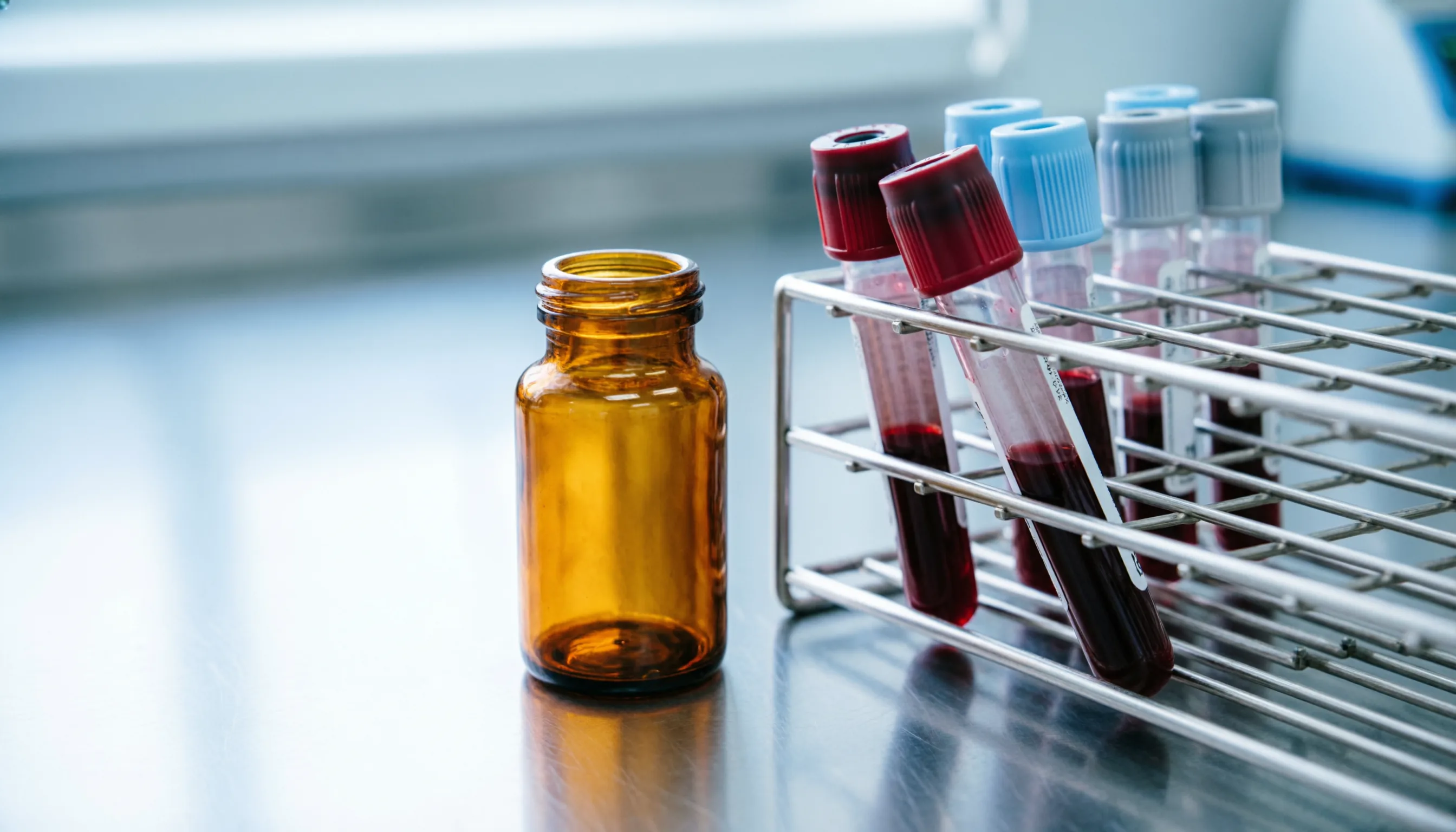 Frasco de testosterona inyectable junto a tubos de muestra de sangre en laboratorio clínico